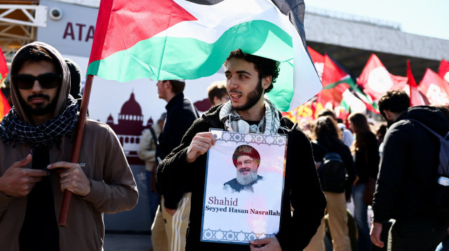 מפגין בעד משט סומוד ברומא, מחזיק תמונה של נסראללה (צילום: רויטרס)