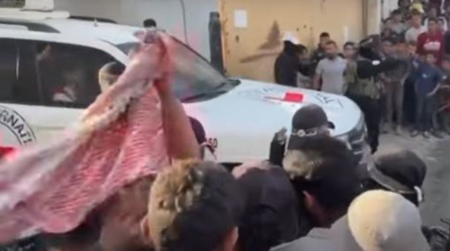 רכבי הצלב האדום ובהם החטופים בין המון עזתי, מאובטחים בידי חמאס (צילום: רשתות ערביות)