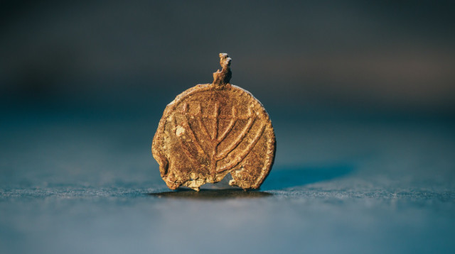 תליון עופרת נדיר, בן כ-1,300 שנה עם סמל המנורה (צילום: אליהו ינאי, עיר דוד)