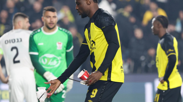 ג'ונבוסקו קאלו שחקן בית"ר ירושלים מפנה כוסות שנזרקו לכר הדשא (צילום: דני מרון)