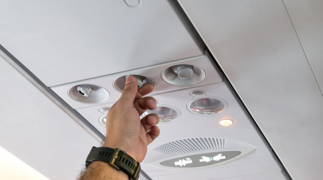 נוסע מכוון את המזגן בטיסה (צילום: שאטרסטוק)