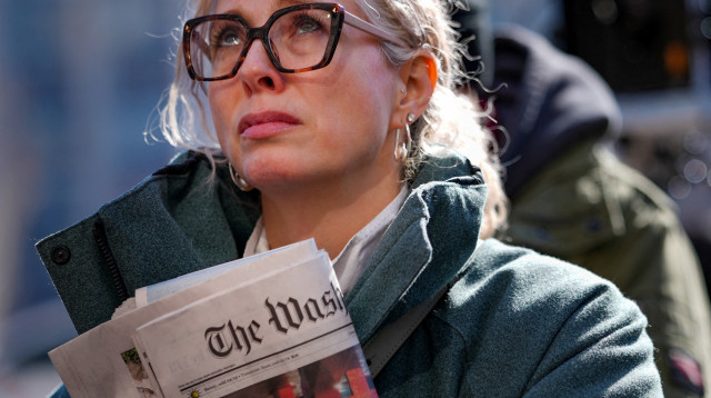 אישה מחזיקה בעיתון ה"וושינגטון פוסט" (צילום: רויטרס)