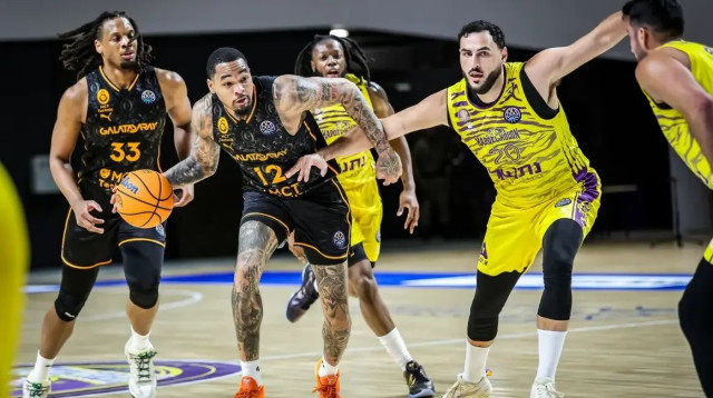 עידן זלמנסון שחקן הפועל חולון מול ג'יימס פאלמר ג'וניור שחקן גלאטסראיי (צילום: אתר רשמי, פיב"א)