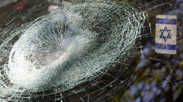 דגל ישראל משתקף מחלון מנופץ (צילום: Odd ANDERSEN / AFP via Getty Images)