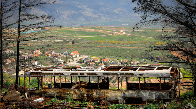 אוטובוס שרוף על רקע של מטולה (צילום: Chen Leopold/Flash90)