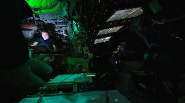 האסטרונאוטית כריסטינה קוצ' קוראת מתוך טאבלט באור מעומעם באוריון. מימינה האסטרונאוט הקנדי ג'רמי הנסן  (צילום: נאס"א)