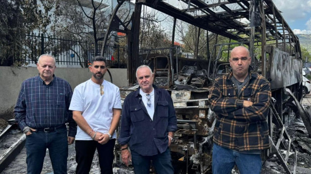 משפחת סגל ובן עמי (מימין) ליד אוטובוס החברה שהוצת בחודש שעבר (צילום: ללא)
