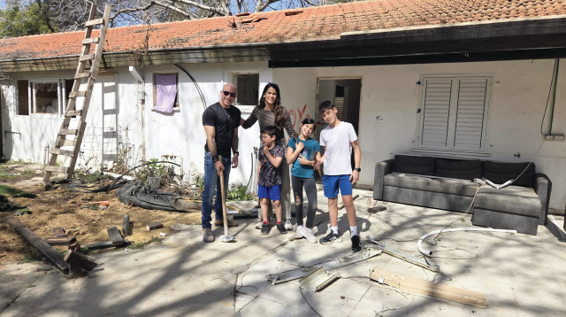 בני וימית אביטל עם ילדיהם על רקע ביתם ההרוס בניר עוז (צילום: פרטי)