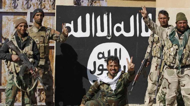 לוחמי מליציה שיעית ליד דגל דאעש בתיכרית (צילום: רויטרס)