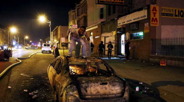 מפגין על גג מכונית בוערת בבולטימור (צילום: רויטרס)