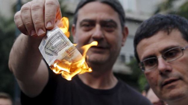 אדם שורף יורו במחאה ביוון (צילום: רויטרס)