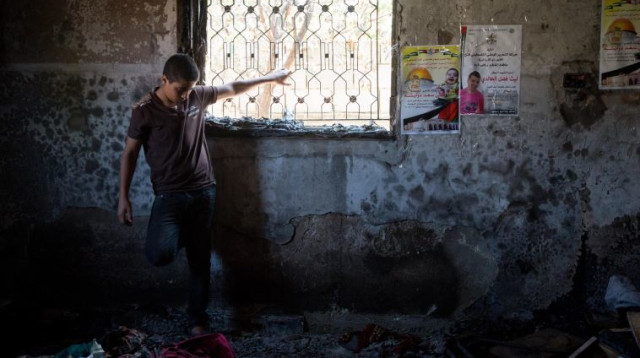 נער פלסטיני מביט על הנזק בבית שהוצת בדומא  (צילום: מרים אלסטר, פלאש 90)