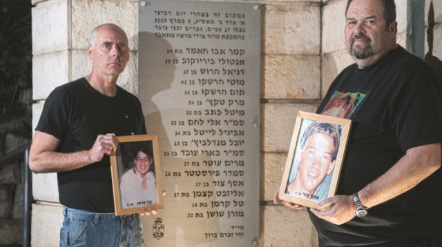 רון קרמן (משמאל) ויוסי צור עם תמונות ילדיהם באנדרטה לזכר נרצחי הפיגוע בקו 37 (צילום: דורון גולן, סוכנות ג'יני)