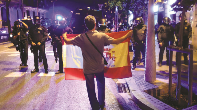 אדם מחזיק דגל קטלוניה מול שוטרים בברצלונה (צילום: רויטרס)