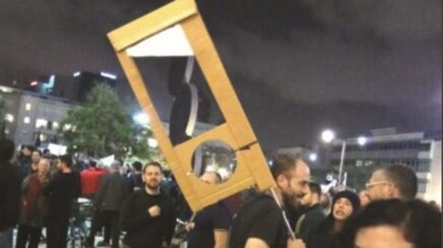 עמית ברין מניף את שלט הגיליוטינה (צילום: ישי פרידמן, מקור ראשון)