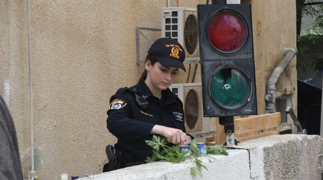 שוטרת מדליקה נרות בכניסה למכינה (צילום: אבשלום ששוני)