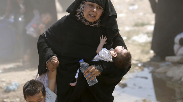 פליטה סורית חוצה את הגבול לטורקיה עם ילדיה (צילום: רויטרס)