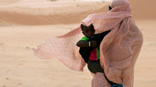 אישה מגנה על בנה מפני הרוח במאוריטניה, מערב אפריקה  (צילום: רויטרס)