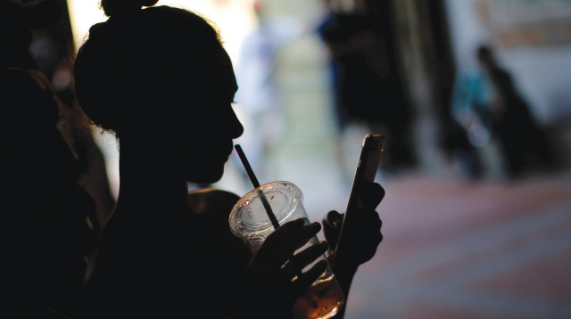 אילוסטרציה - בחורה מסתכלת בסלולרי (צילום: רויטרס)