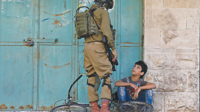 חייל צה"ל ונער פלסטיני (צילום: רויטרס)