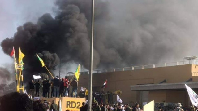 מפגינים שורפים את החומה של שגרירות ארה"ב בבגדד (צילום: מסך)