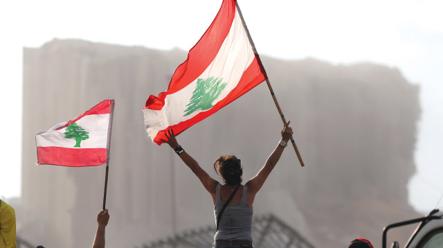 תושבי ביירות ברקע הריסות הנמל לאחר הפיצוץ (צילום: רויטרס)