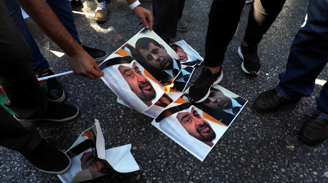 פלסטינים שורפים את תמונותיהם של בן זאיד ודחלאן במחאה על ההסכם בין ישראל לאיחוד האמירויות (צילום: REUTERS/Mohamad Torokman)