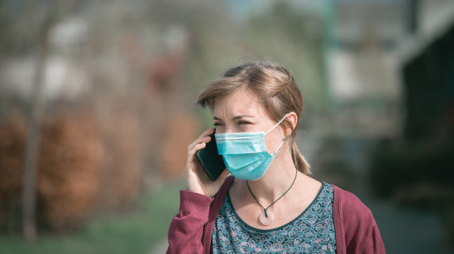 אישה עם מסכה מדברת בטלפון (צילום: אינג אימג')