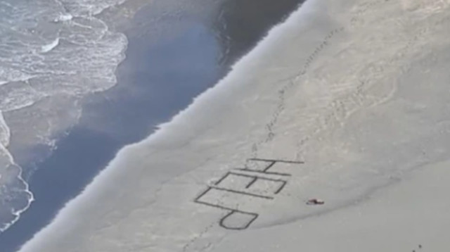 הזעקה לעזרה שכתב הגולש בחול (צילום: Surf Life Saving NZ)