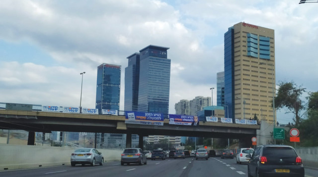 שלטים לא חוקיים תלויים על גשר מעל נתיבי איילון (צילום: חוצות זהב)