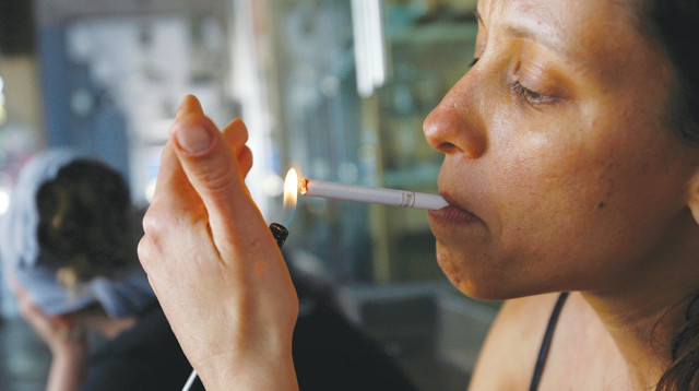 אישה מדליקה סיגריה בתל אביב - ארכיון - צילום רויטרס (צילום: רויטרס)