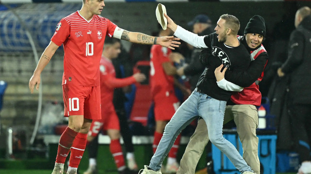 גרניט ג'אקה קפטן נבחרת שוויץ עם אוהד שפרץ למגרש (צילום: GettyImages, SEBASTIEN BOZON/AFP)