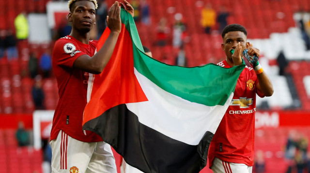 שחקן מנצ'סטר יונייטד פול פוגבה עם אמאד דיאלו מניפים את דגל פלסטין לאחר המשחק מול פולהאם (צילום: רויטרס)