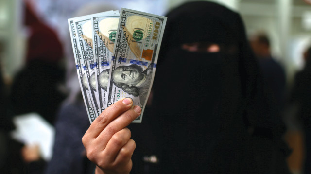 טרוריסט רעול פנים מחזיק כסף דולרים ביד  (צילום: רויטרס)