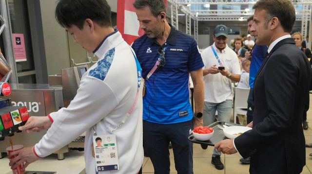 נשיא צרפת עמנואל מקרון סועד בכפר האולימפי בפריז (צילום: GettyImages, MICHEL EULER/POOL/AFP)