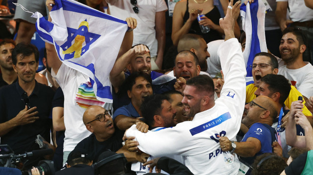 פיטר פלצ'יק עם דגל החטופים באולימפיאדה אחרי הזכייה בארד (צילום: REUTERS/Kim Kyung-Hoon)