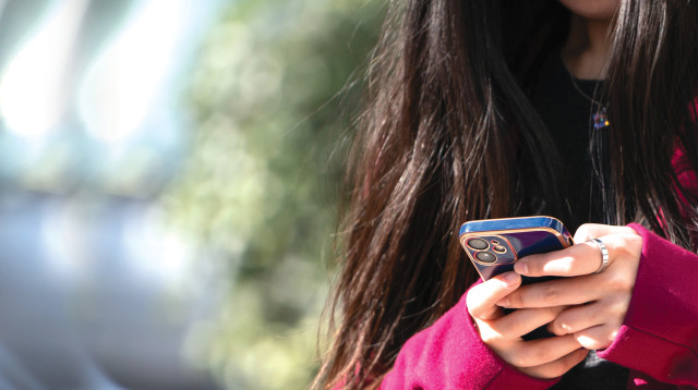 מילים שליליות ברשתות פוגעות בבריאות שלנו. אישה מחזיקה טלפון נייד (צילום: גטי אימג')