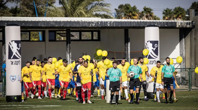 שחקני מכבי יבנה לצד שחקני הפועל אזור, טקס יום השנה ל-7 באוקטובר (צילום: אתר רשמי, ההתאחדות לכדורגל)