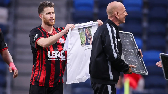 גיא מלמד מחזיק חולצה עם תמונתה של רומי גונן שחטופה בעזה (צילום: מאור אלקסלסי)