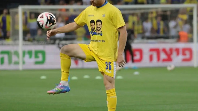 שחקן מכבי תל אביב עידו שחר. על חולצתו תמונתם של החטופים גלי ברמן, זיוי ברמן (צילום: אודי ציטיאט)