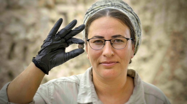 אסתר ראקוב-מלט, מנהלת החפירה מטעם רשות העתיקות, עם המטבע (צילום: אסף פרי, עיר דוד)