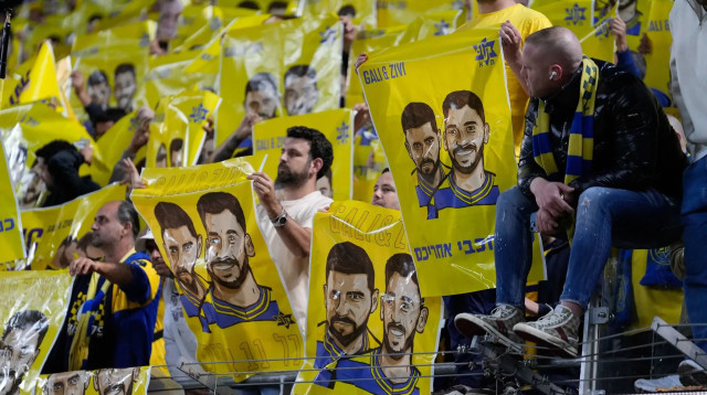 אוהדי מכבי תל אביב עם שלטים שקוראים לשחרור גלי וזיוי ברמן, ושאר החטופים (צילום: שירה קז)