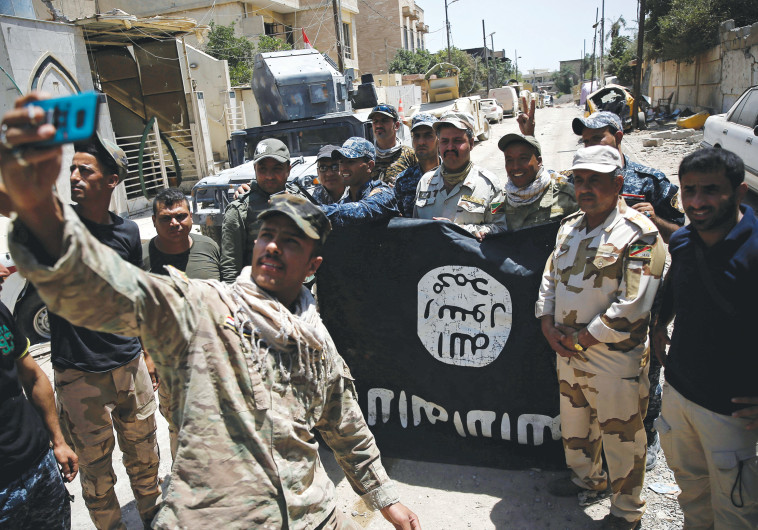 לוחמי הצבא העיראקי עם דגל דאעש. (צילום:רויטרס)
