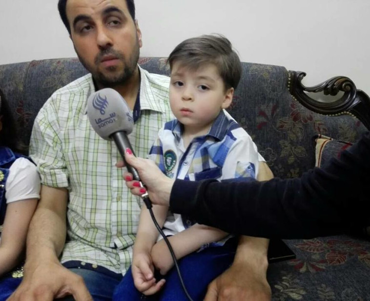 עומראן דקניש כיום, בריא ויושב על ברכי אביו. צילום: פייסבוק