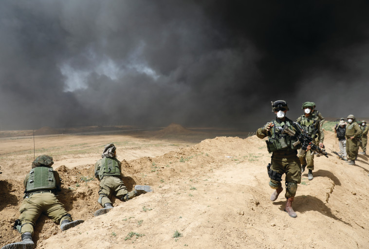 חיילי צה"ל מול הצמיגים הבוערים בעזה. צילום: AFP