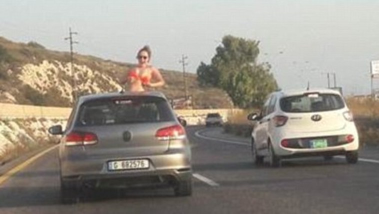 הצעירה מורידה את החזייה שלה לעיני הנהגים בכביש. צילום מסך