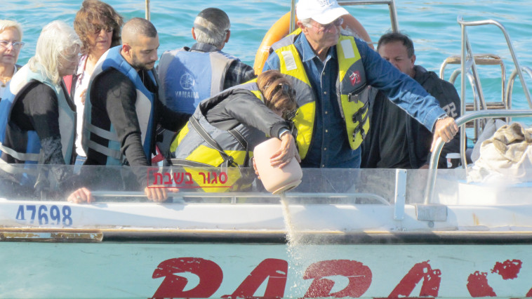 מזל, בת זוגו של עזרא, שופכת את עפרו לים. צילום: נתן זהבי