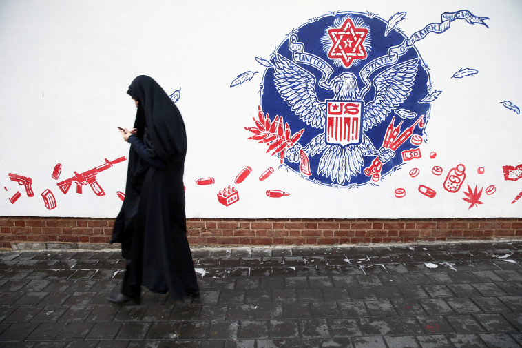 אישה איראנית חולפת על פני גרפיטי אנטי אמריקאי על שגרירות ארה''ב בטהרן  (צילום: רויטרס)