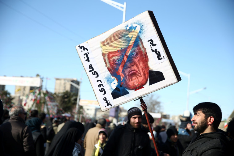 מפגין עם שלט נגד נשיא ארה"ב דונלד טראמפ בהפגנה בטהרן. צילום: רויטרס