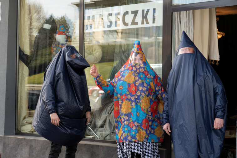 אנשים בפולין לובשים חליפות להגנה מקורונה שנתפרו על ידי תושבת המדינה (צילום: REUTERS/Jadwiga Figula)